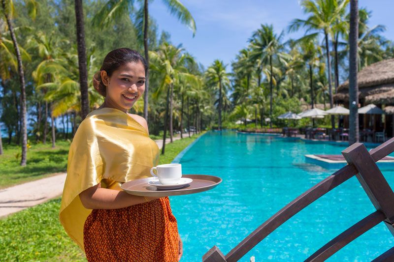 Eine Hotelmitarbeiterin im The Haven Khao Lak in Thailand serviert Kaffee am Pool, aufgenommen von einem Hotelfotografen.