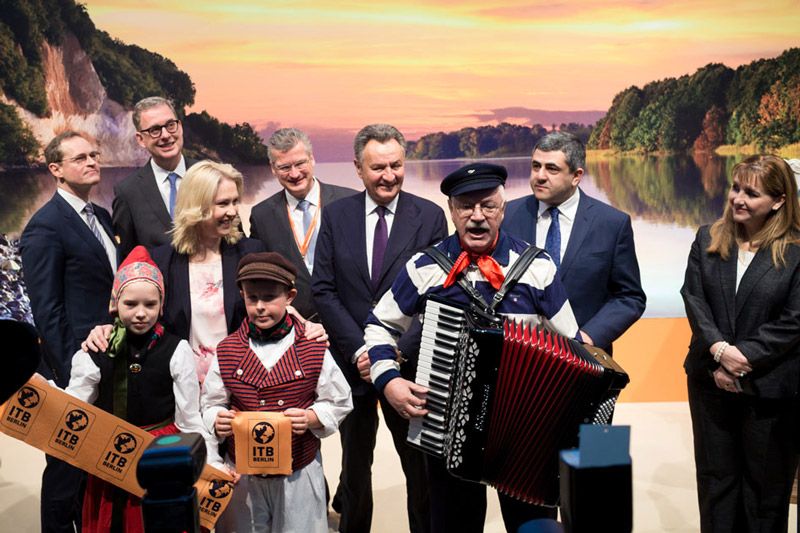 Eröffnungsfeier der ITB Berlin 2018 mit einem Akkordeonspieler, Kindern in traditionellen Kostümen und Vertretern aus der Politik.