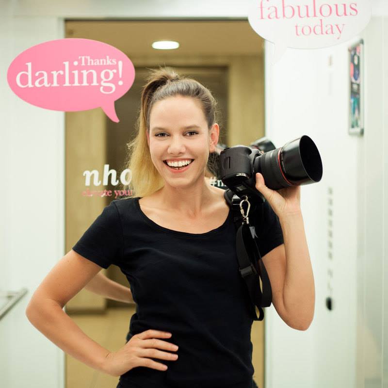Grit Erlebach, Eventfotograf Berlin, lächelt in die Kamera und hält ihre professionelle Ausrüstung bereit.

