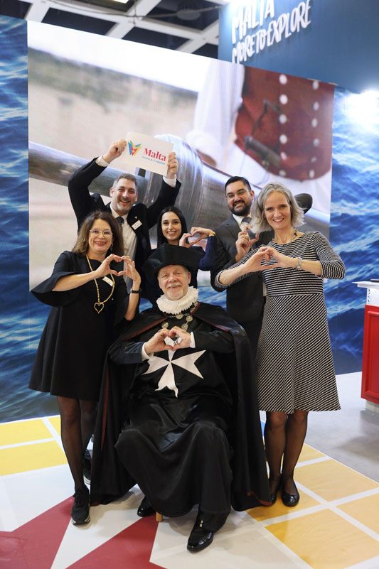 Das Team von Malta Tourismus auf der ITB Berlin 2023, lächelnd und Herzsymbole formend.